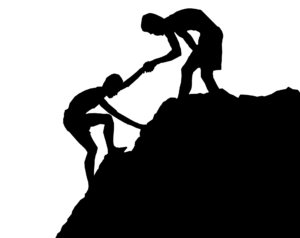 Sillouette of someone helping another person up a mountain