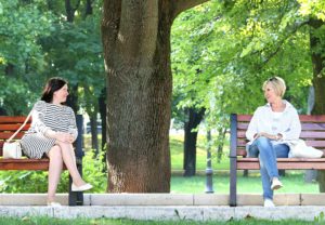 Two women having a conversation across a divide of 2 benches